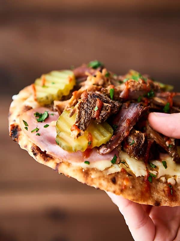 #ad This mini cuban naan pizzas might just be the easiest dinner yet! Slow cooker pork paired with ham, naan bread, swiss cheese, mustard, and pickles! 15 minute dinner. showmetheyummy.com Made in partnership w/ @smithfieldfoods #RealFlavorRealFast #pizza