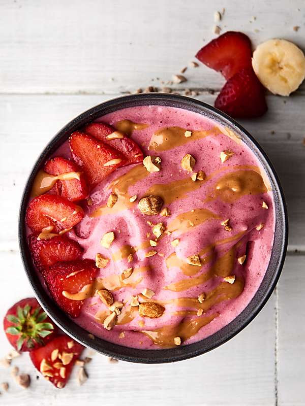 Peanut butter jelly smoothie bowl with sliced strawberries above