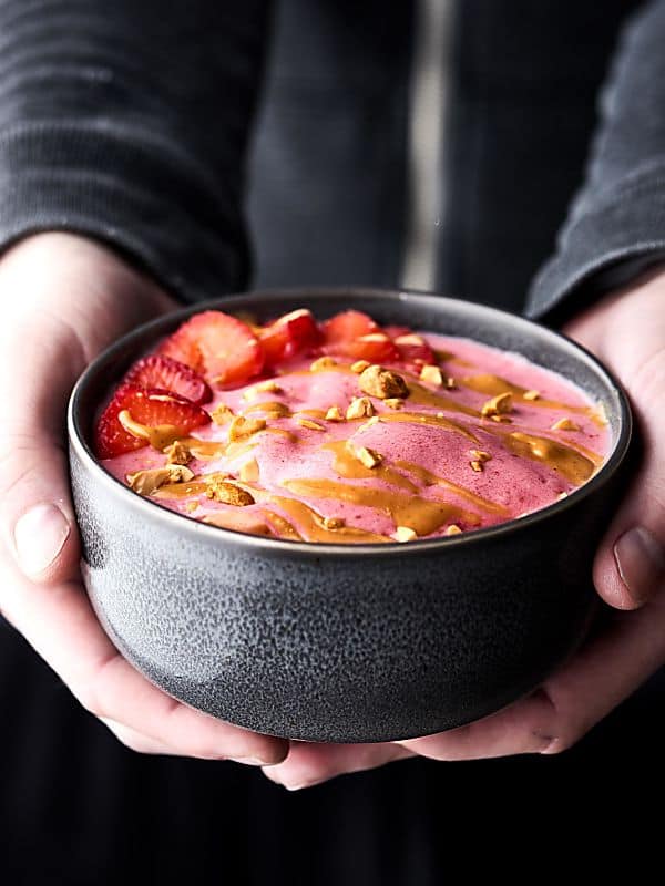 Peanut butter jelly smoothie bowl held two hands