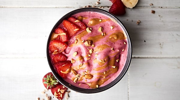 A favorite sandwich from your childhood turned into a healthy smoothie bowl: these peanut butter and jelly smoothie bowls are absolutely delicious! Full of frozen strawberries and all natural peanut butter, they really do taste like the childhood classic! showmetheyummy.com #smoothie #peanutbutter #jelly
