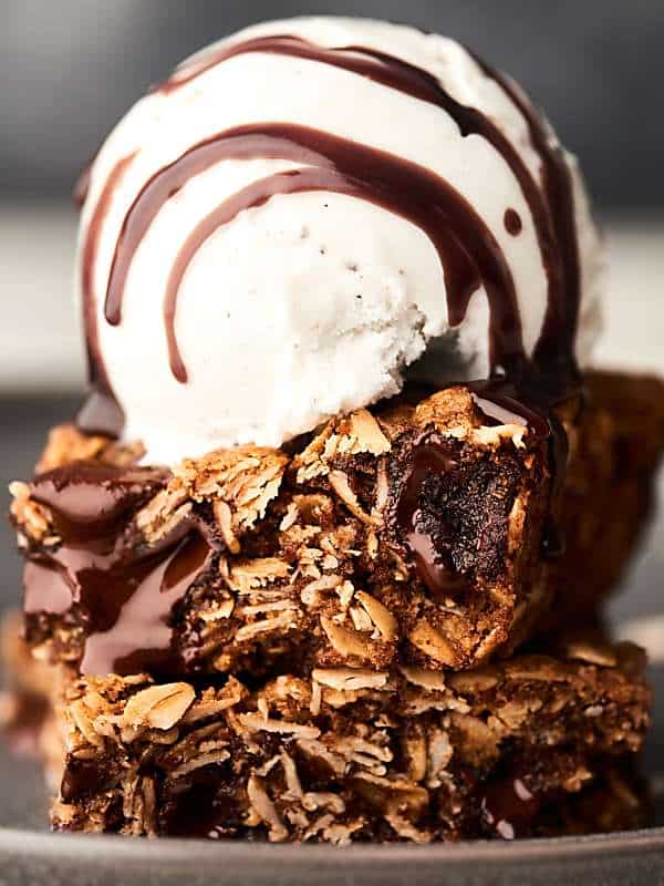 two cookie bars stacked with scoop of ice cream on top and chocolate drizzle