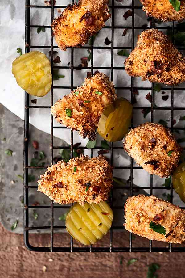 Air fryer chicken nuggets on cooling rack with pickles above