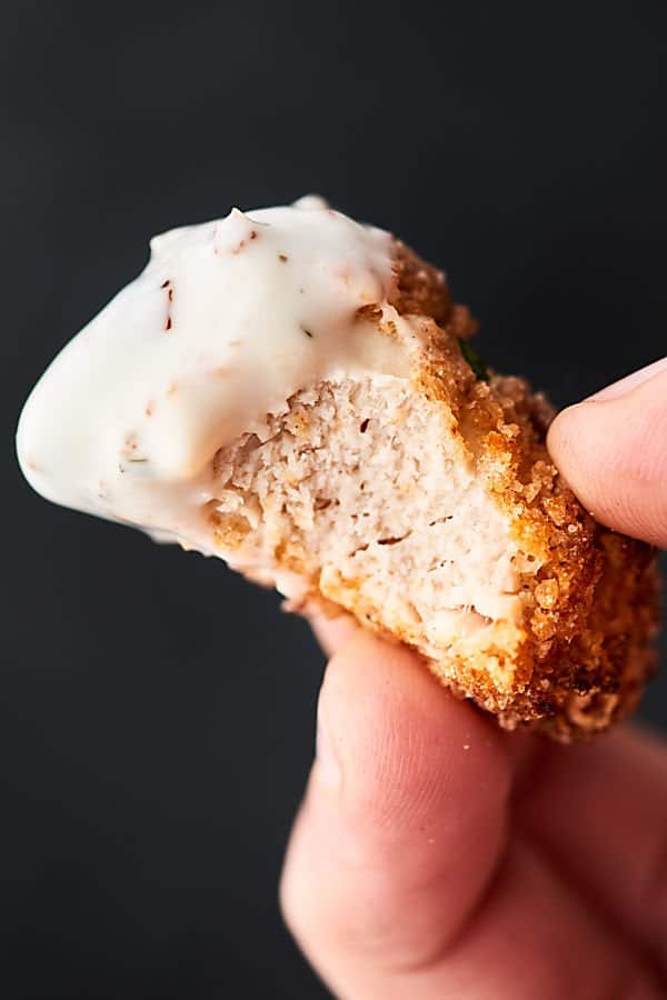 Chicken nugget held with bite out and dip