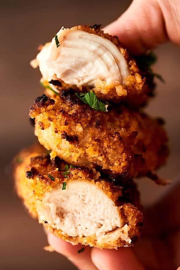 three chicken tenders stacked and held