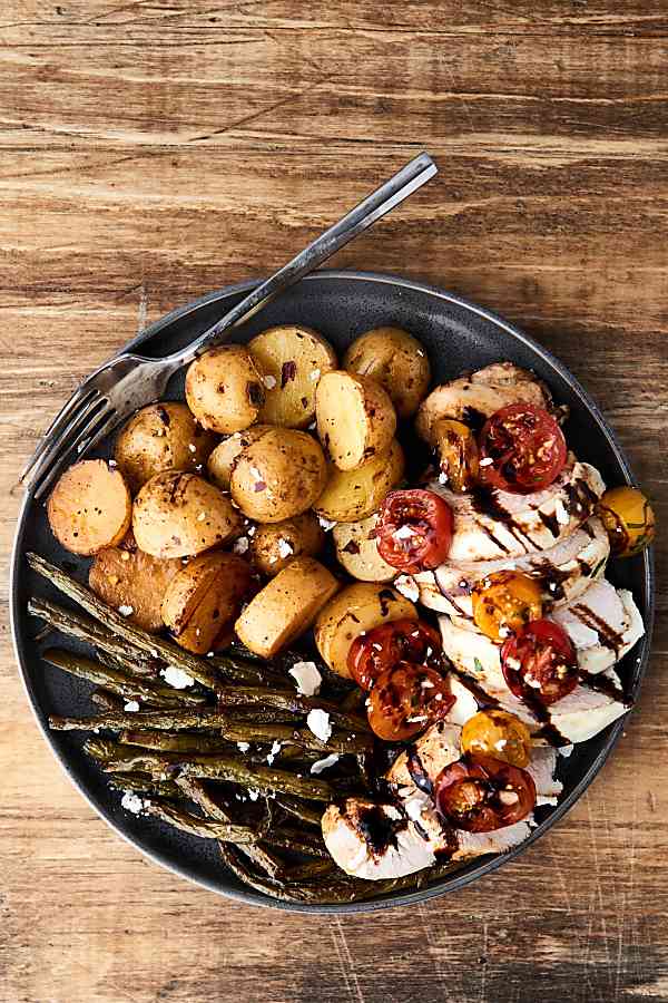 bruschetta chicken on plate with roasted asparagus and potatoes above