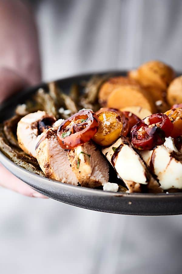 plate of bruschetta chicken with roasted veggies held