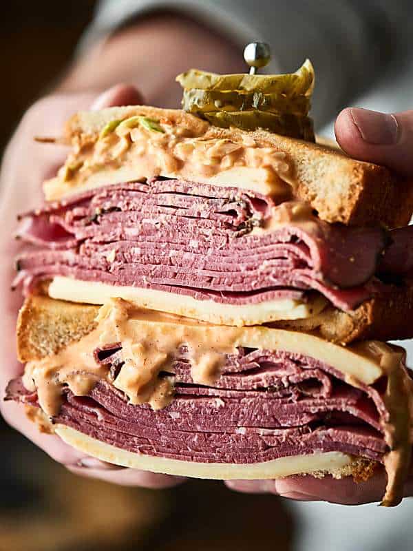 Two halves of pastrami sandwich stacked and held