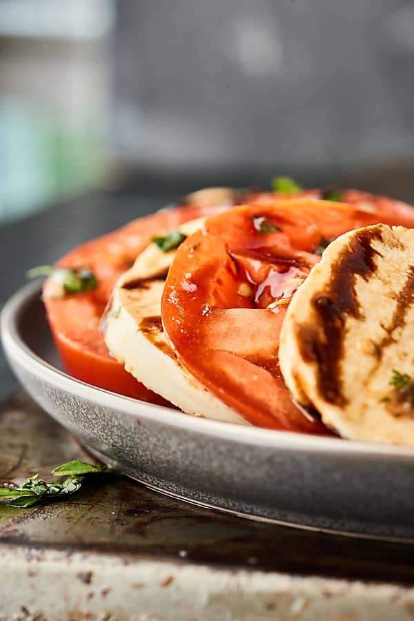 This Easy Caprese Salad is an easy, fresh summer classic! Juicy sliced tomatoes and creamy mozzarella seasoned with extra virgin olive oil, balsamic vinegar, garlic, fresh basil, and salt. Don't forget the extra drizzle of balsamic glaze! showmetheyummy.com #caprese #salad