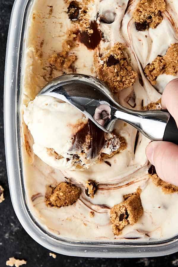 cookie dough ice cream being scooped out of tupperware above