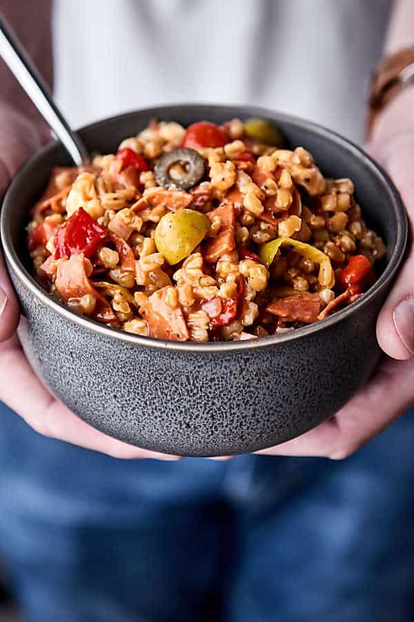 bowl of antiipasto farro salad held two hands