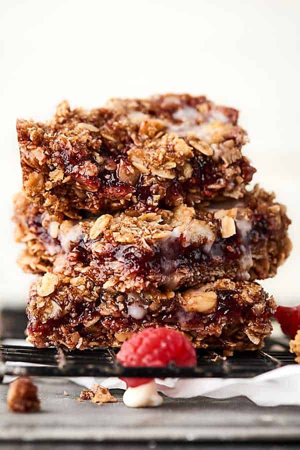 These Vegan Raspberry Oatmeal Bars are SO easy and tasty. This vegan gluten free dessert is loaded with oats, brown sugar, coconut oil, walnuts, and your choice of preserves or jam! showmetheyummy.com #vegan #dessert #oatmealbars #raspberry