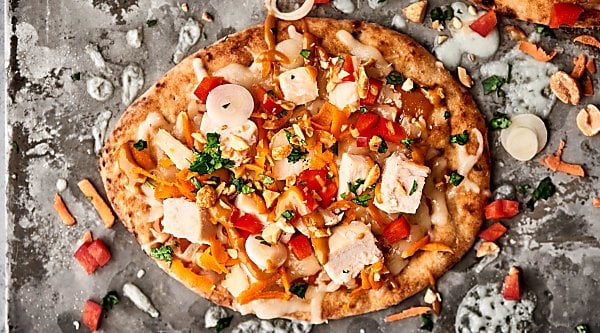 Easy Thai Chicken Naan Pizza Recipe. Store bought naan topped with a homemade easy peanut sauce, monterey jack cheese, chicken, carrots, peppers, cilantro, green onion, and peanuts! SO quick and delicious! showmetheyummy.com #naan #pizza #thai #chicken