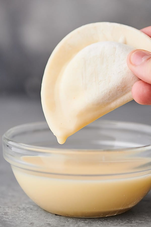 pierogie being dipped into bowl of dressing