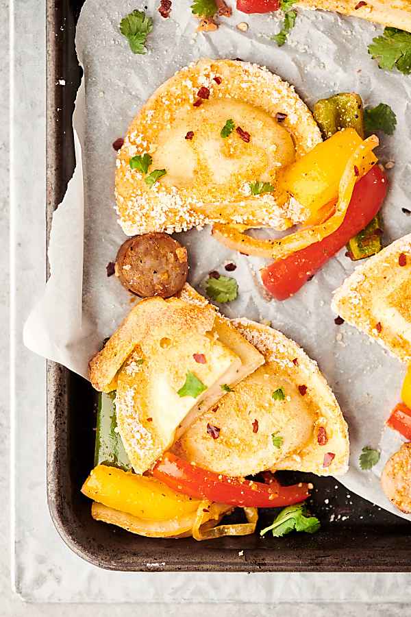pierogies with sausage and peppers on sheet pan above