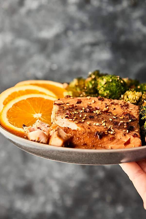 plate of asian salmon and broccoli held