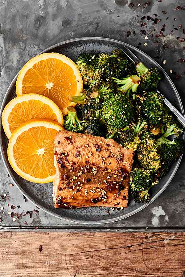 plate of salmon, broccoli, and orange slices above