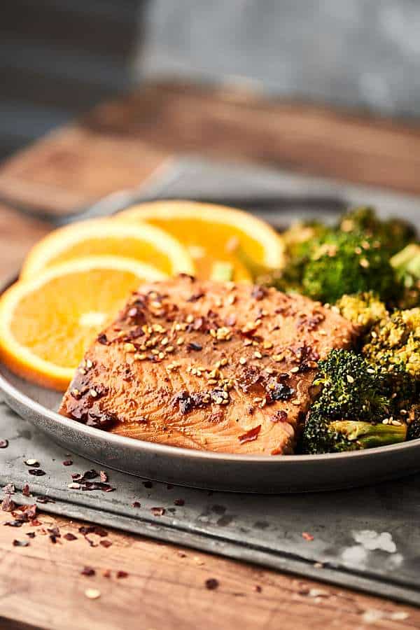 plate of asian salmon and broccoli on plate with orange slices