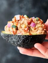 A spicy tuna roll inspired filling: olive oil mayo, sriracha, vinegar, soy sauce, sesame oil, canned cooked tuna, cucumber, and red bell pepper stuffed into an avocado for a quick, easy, healthy, meal prep, make ahead lunch! showmetheyummy.com #tunasalad #spicytuna #avocado #mealprep #healthylunch #lowcarb