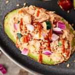 A spicy tuna roll inspired filling: olive oil mayo, sriracha, vinegar, soy sauce, sesame oil, canned cooked tuna, cucumber, and red bell pepper stuffed into an avocado for a quick, easy, healthy, meal prep, make ahead lunch! showmetheyummy.com #tunasalad #spicytuna #avocado #mealprep #healthylunch #lowcarb