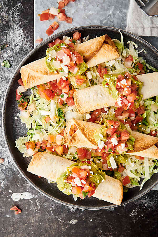 Four air fryer chicken taquitos on a plate above