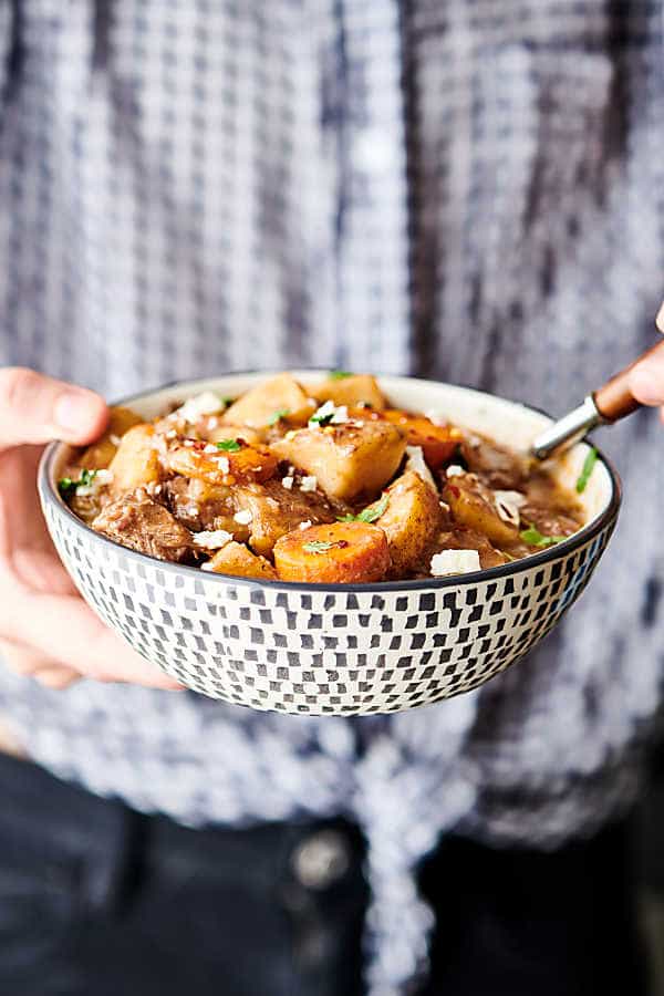 bowl of beef stew held two hands