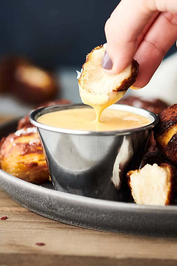 air fryer pretzel bite being dipped in cheese sauce