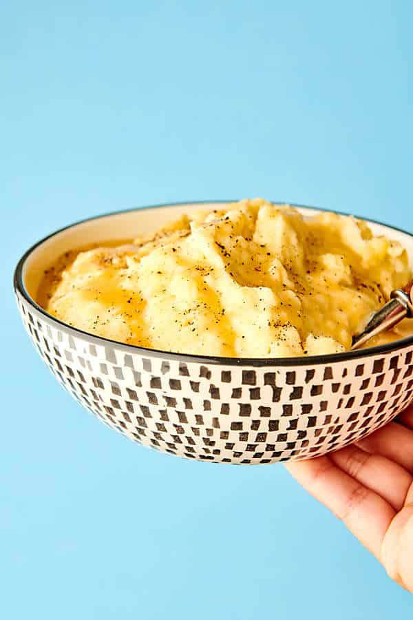 bowl of mashed potatoes held blue background