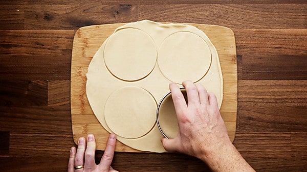 pie dough being cut with cookie cutter