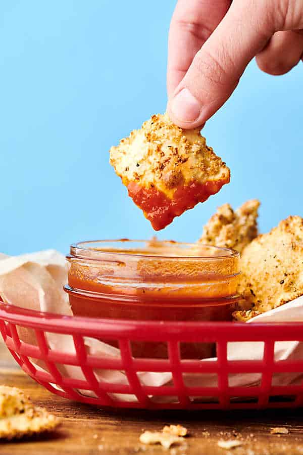 Air fryer fried ravioli being dipped in marinara sauce