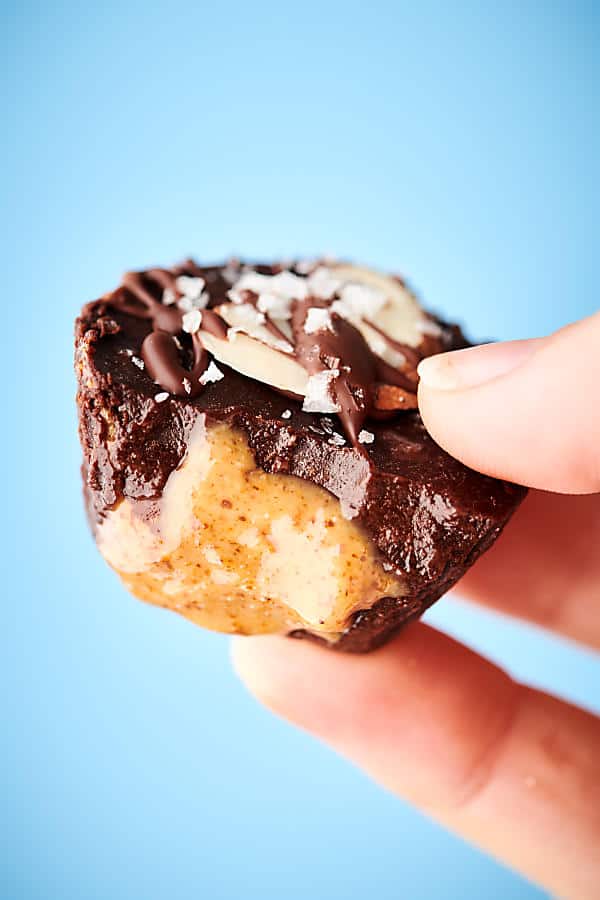 homemade almond butter cup held blue background