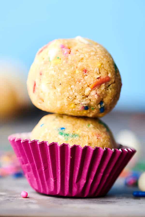 two funfetti edible cookie dough balls stacked in mini muffin wrapper
