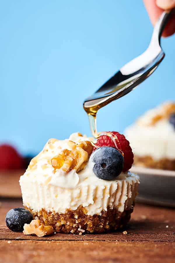 lemon walnut no bake cheesecake with honey being drizzled over with spoon