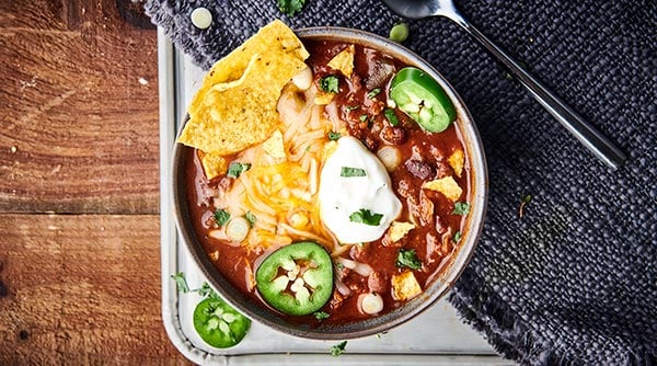 This Instant Pot Chili Recipe is SO quick, easy, and loaded with bacon, beef, beer (optional), broth, tomato sauce, veggies, beans, and spices! Serve with optional, but highly recommended cornbread, shredded cheese, and sour cream! SO hearty and cozy. showmetheyummy.com #instantpot #beef #chili