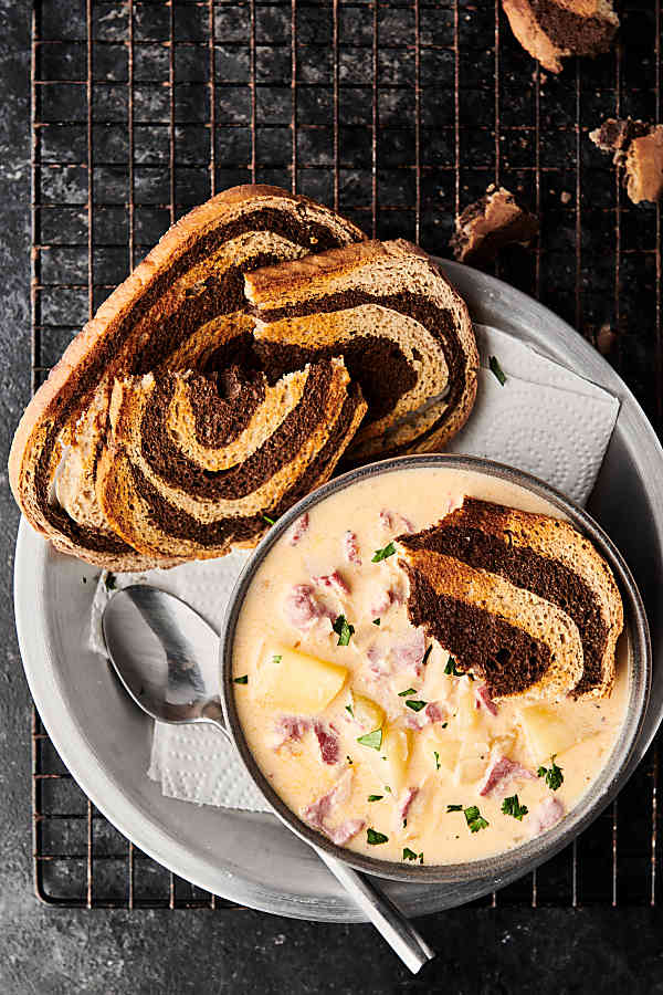 Bowl of reuben soup on a plate with toasted rye bread above
