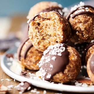 A healthy twist on the classic candy bar, you're going to LOVE these Almond Joy Energy Bites. These are naturally sweetened with dates and loaded with almond butter (or nut butter of choice), a touch of coconut oil, oats (gluten free certified if necessary), unsweetened flaked coconut, vanilla and almond extract, salt and a drizzled with chocolate! Vegan. Gluten free. showmetheyummy.com #vegan #glutenfree #almondjoy #energybites #healthy #snack