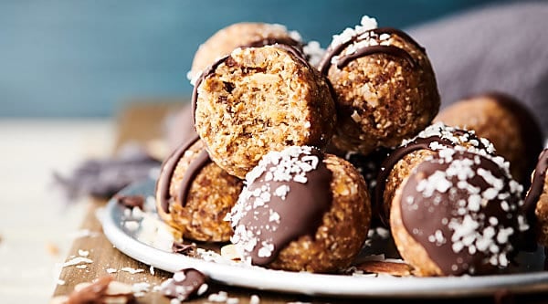 A healthy twist on the classic candy bar, you're going to LOVE these Almond Joy Energy Bites. These are naturally sweetened with dates and loaded with almond butter (or nut butter of choice), a touch of coconut oil, oats (gluten free certified if necessary), unsweetened flaked coconut, vanilla and almond extract, salt and a drizzled with chocolate! Vegan. Gluten free. showmetheyummy.com #vegan #glutenfree #almondjoy #energybites #healthy #snack