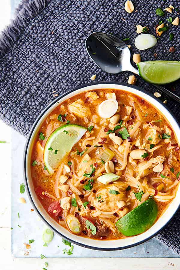 bowl of coconut curry chicken noodle soup with lime wedges above