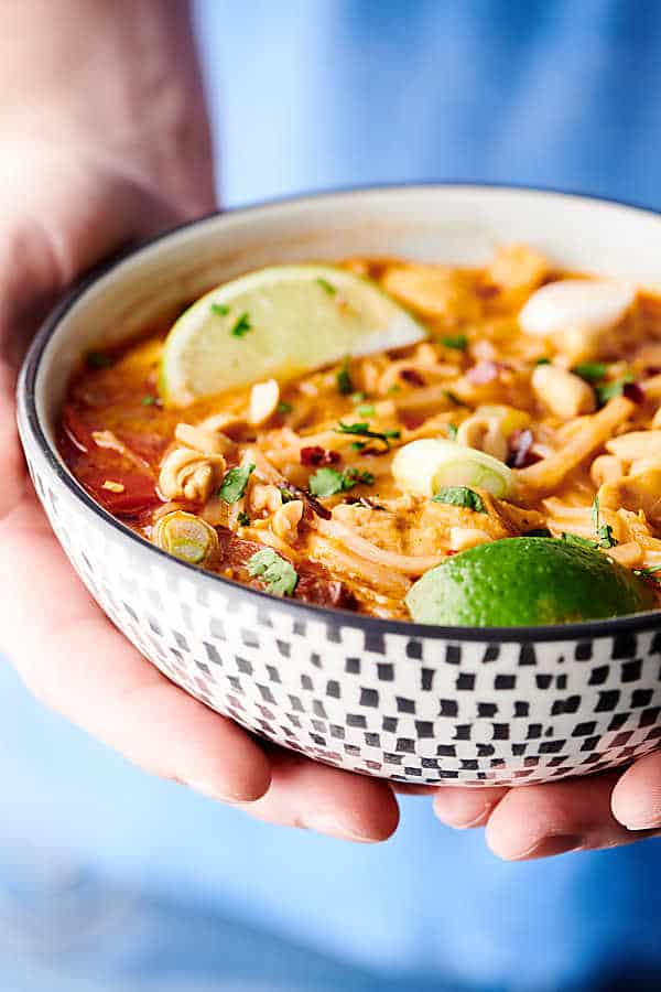 Bowl of coconut curry chicken noodle soup held