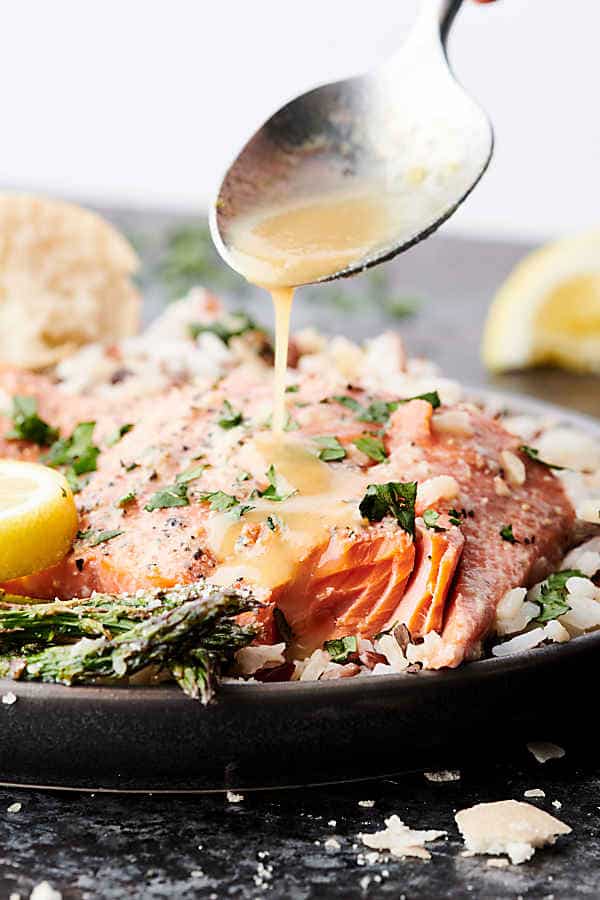 dressing being drizzled over salmon on plate