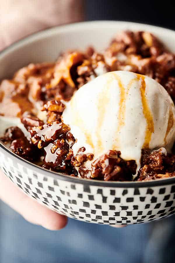 slow cooker carrot cake in bowl with scoop of ice cream held