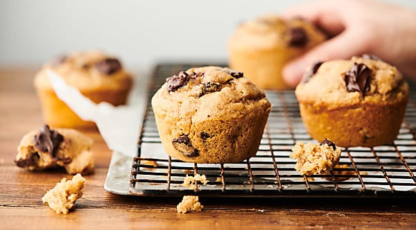 These Healthy Banana Pancake Muffins are loaded with bananas, pure maple syrup, all natural peanut butter, fat free buttermilk, egg, vanilla extract, whole grain protein pancake mix, cinnamon, and dark chocolate chunks! Quick, healthy, and delicious! Freezer friendly. Less than 250 calories per muffin! showmetheyummy.com #healthy #banana #pancake #muffins #chocolate
