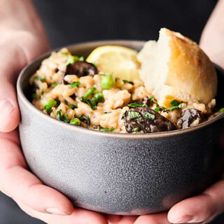 Instant Pot Mushroom Risotto. A classic made in the pressure cooker and loaded with butter, onions, spices, baby belly mushrooms, garlic, Arborio rice, a splash of wine, vegetable broth, baby spinach, peas, three kinds of cheese: asiago, romano, and parmesan, and fresh lemon juice/zest! A decadent vegetarian main or a creamy side dish to your favorite protein! showmetheyummy.com #instantpot #mushroom #risotto #glutenfree #vegetarian