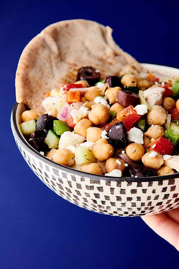 bowl of chickpea egg salad held blue background