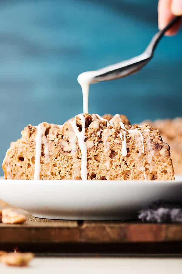 Icing being drizzled over slice of pancake coffee cake