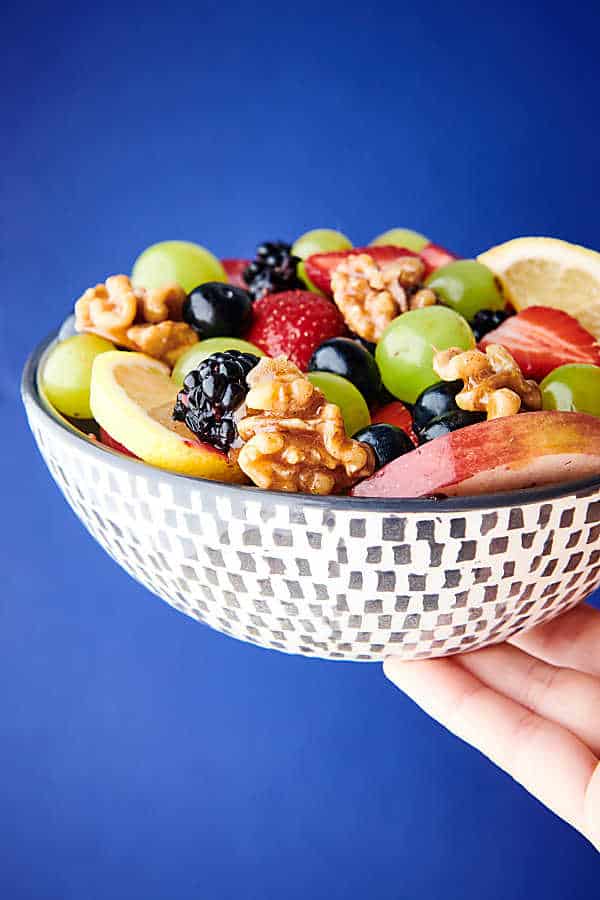 fruit salad with honey walnuts blue background