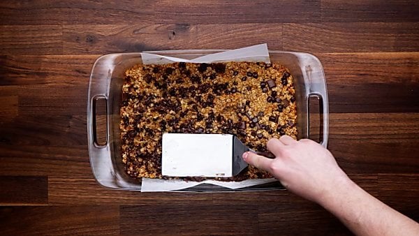 baked granola bars being pressed with spatula