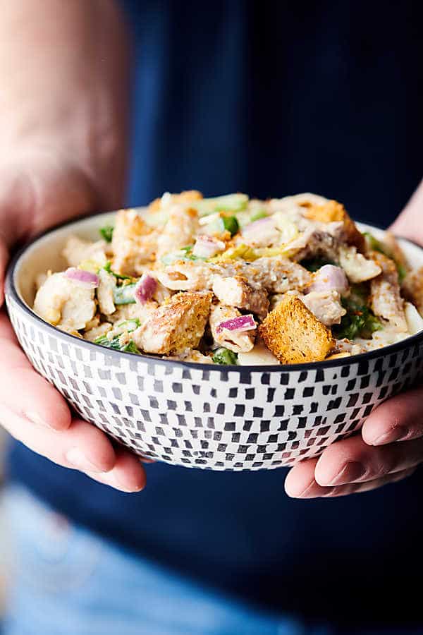 healthy chicken caesar pasta salad holding in hands