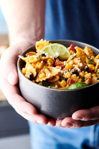 mexican street corn pasta salad holding in hands