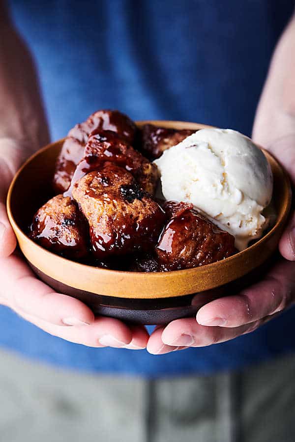 Slow Cooker Cherry Cobbler holding bowl with ice cream