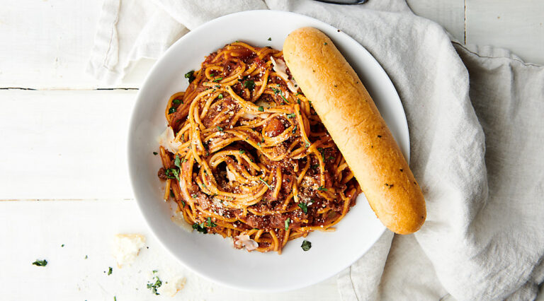 plate of spaghetti with breadstick above
